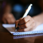 Image of someone writing in a notebook for the public engagement and literacy research issue