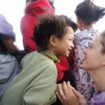 a boy and a woman share a moment of joy together behind a group of children