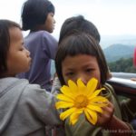 a young girl shows the camera a large yellow flower