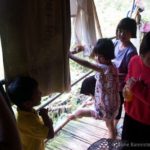four children talk and play on a front porch with towels hanging from the ceiling