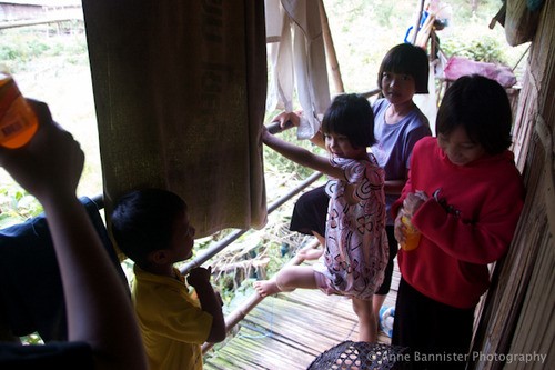 four children talk and play on a front porch with towels hanging from the ceiling