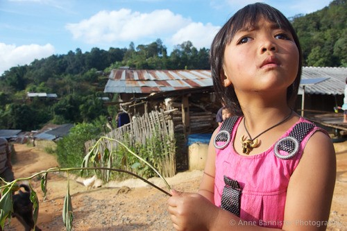 a young girl in a pink outfit looks at the camera while holding a plant