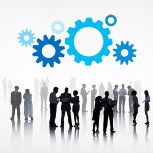 a party of people sits in the shadows beneath large blue gears