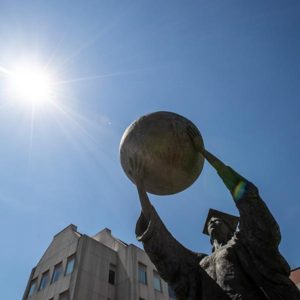 The Citizen Scholar statue raises a globe to the sky in front of Missouri State's Strong Hall