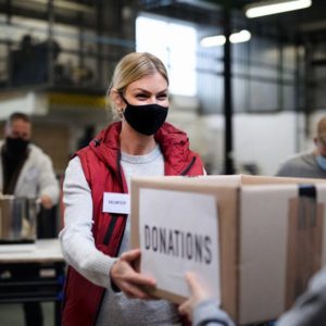 a volunteer accepts donations in a box with a pleasant look