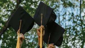 Several hands holding up graduation caps.